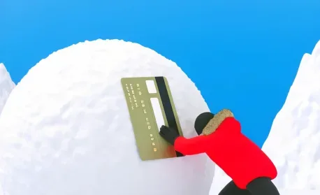 Ilustração em 3D de fundo azul e cenário nevado, onde uma pessoa vestindo um casaco vermelho com capuz de pelo tenta empurrar ou travar uma enorme bola de neve. Incrustada na lateral da bola de neve está uma imitação gigante de um cartão de crédito dourado com tarja preta, simbolizando o peso do end