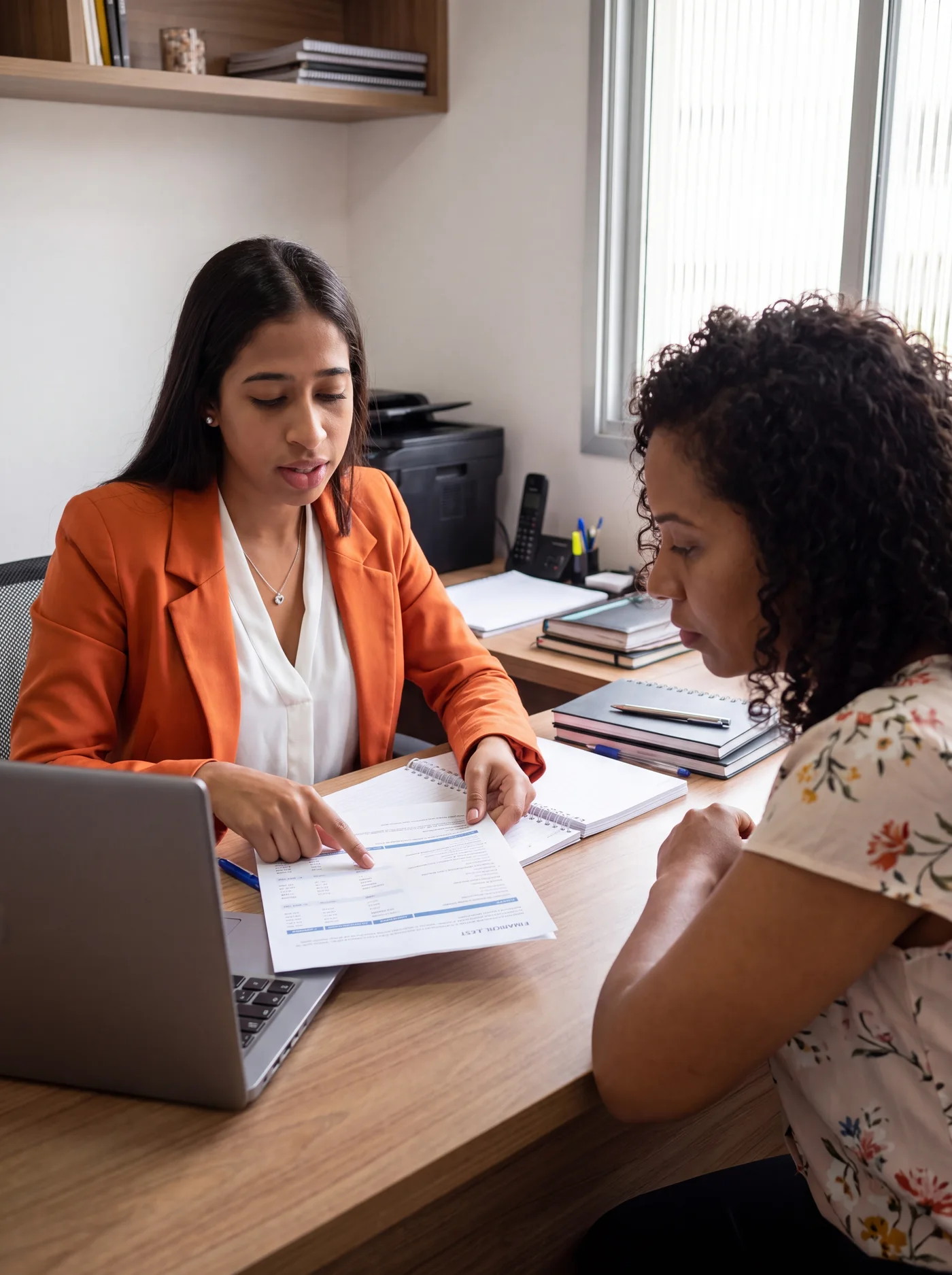 Duas mulheres conversando sobre um documento durante um atendimento.