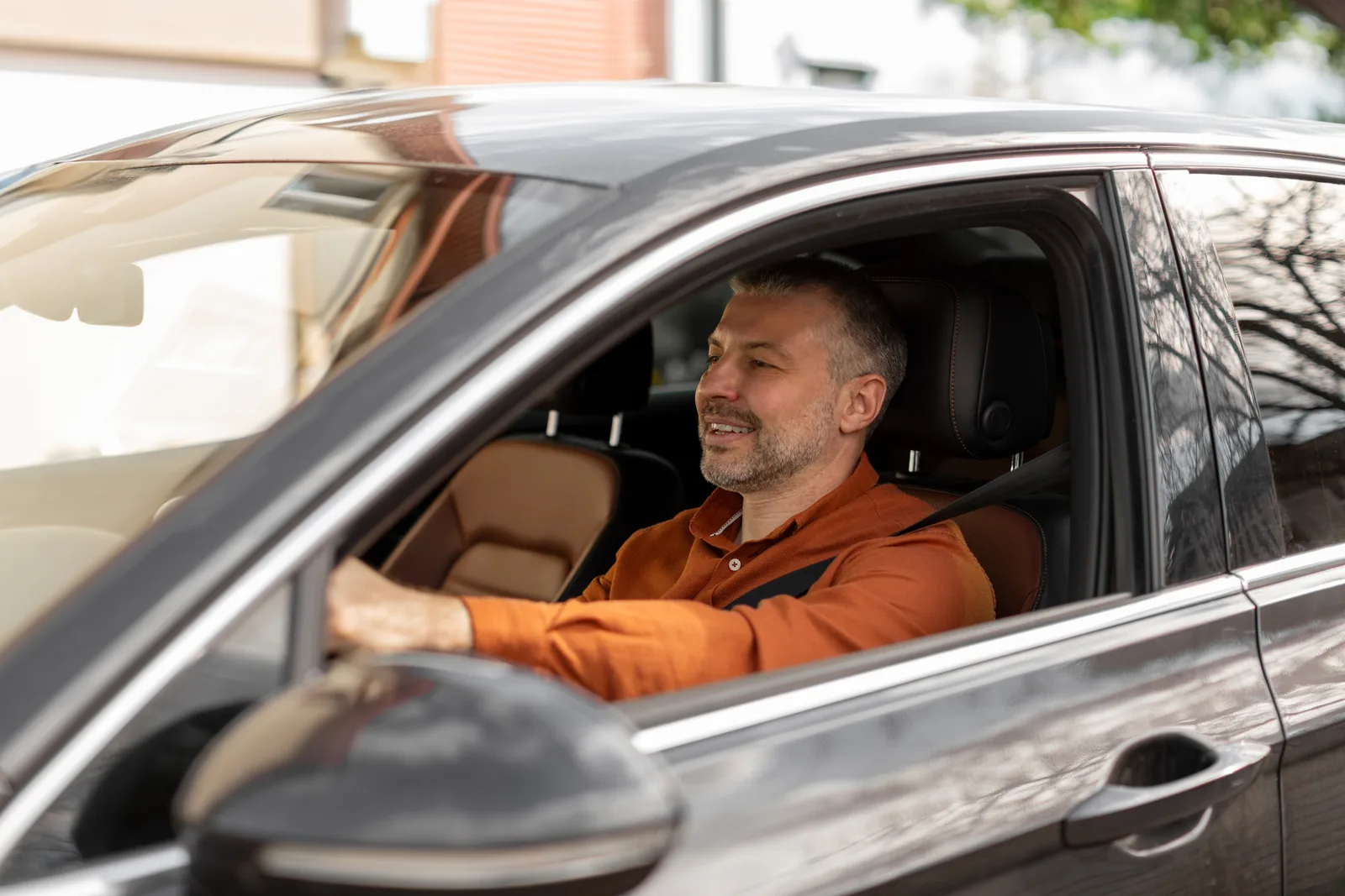 Homem com cinto de segurança ao volante de um carro.
